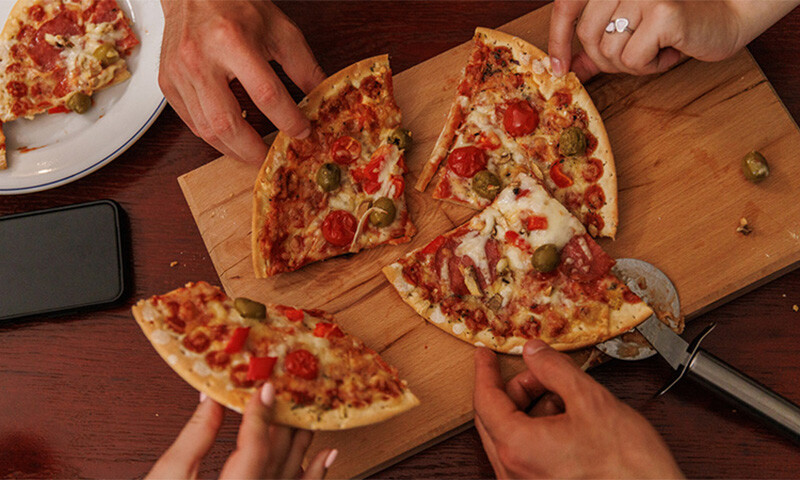 hands grabbing slices of pizza